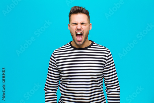 Fotografía young hispanic man shouting aggressively, looking very angry, frustrated, outrag