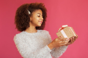Wall Mural - Cute festive girl holding a shiny gift box