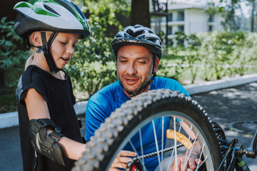 Wall Mural - Cute little girl helping her father to repair bicycle wheel