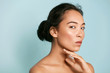 © puhhha - Skin care. Woman with beauty face and healthy facial skin portrait. Beautiful asian girl model with natural makeup touching glowing hydrated skin on blue background closeup. High quality image