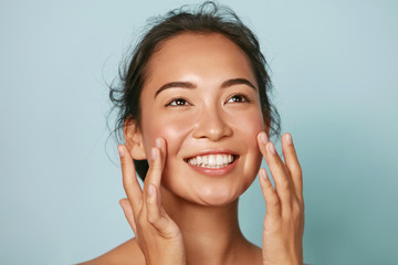 Wall Mural - beauty face. smiling asian woman touching healthy skin portrait. beautiful happy girl model with fre