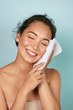 © puhhha - Washing face. Closeup of woman cleaning skin with towel portrait. Beautiful asian girl model wiping facial skin with soft facial towel, removing makeup. High quality studio shot