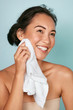 © puhhha - Washing face. Closeup of woman cleaning skin with towel portrait. Beautiful asian girl model wiping facial skin with soft facial towel, removing makeup. High quality studio shot