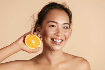 Wall Mural - beauty. smiling woman with radiant face skin and orange portrait. beautiful smiling asian girl model