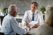 © Drazen - Insurance agent talking with senior clients while analyzing their financial reports in the office.