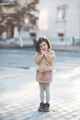 Wall Mural - Cute kid girl 3-4 year old wearing trendy clothes posing in cityoutdoors. Looking at camera. Childhood. Autumn season.