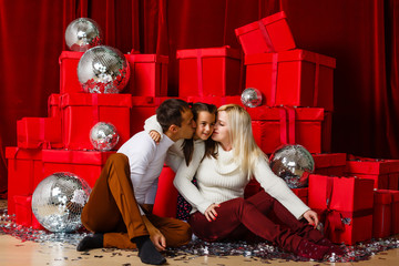 Wall Mural - Happy parents kissing daughter and giving xmas present on bed