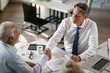 © Drazen - Above view of insurance agent and senior man shaking hands in the office.