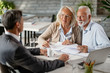 © Drazen - Happy senior couple going through blueprints while talking with real estate agent.