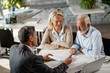 © Drazen - Senior couple reading terms of the contract offered to them by their financial advisor.