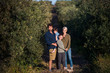 © Halfpoint - Young family with two small children standing outdoors by olive trees.