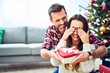 © baranq - Portrait of man surprising girlfriend with present. Family during Christmas celebration