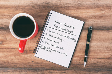 Wall Mural - New Year's Resolutions Concept - Note pad, pen and cup of coffee background.