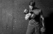 © Srdjan - Young strong muscular sweaty man biceps muscle workout training with heavy dumbbell weight in the gym dark image with shadows real people black and white