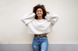 © mimagephotos - smiling african american woman with hands in hair against white wall