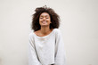 © mimagephotos - smiling african american woman with curly hair against white wall