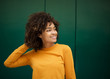 © mimagephotos - beautiful young african american woman smiling with hand in hair by green background