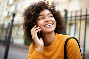 Wall Mural - close up happy african american young woman talking with cellphone outside in city