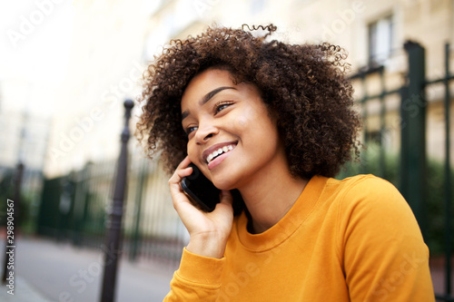 Cuadros en Lienzo happy african american young woman talking with cellphone in city