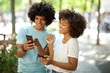 © mimagephotos - happy afro man showing smiling african american young woman cellphone