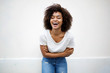 © mimagephotos - happy young african american woman laughing with arms crossed against white background