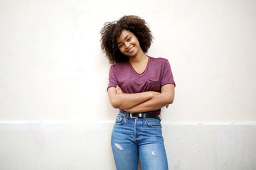 Wall Mural - cool african american girl with arms crossed smiling by white wall