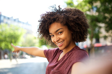 Wall Mural - smiling young african american woman taking selfie and pointing to background