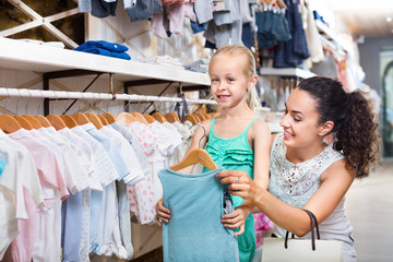 Woman with small girl choosing blue clothes