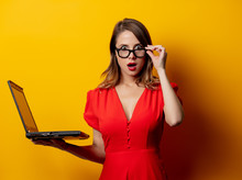 Beautiful Woman In Red Dress With Laptop Computer On Yellow Background
