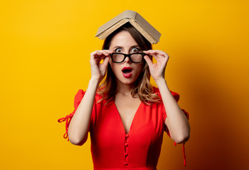 Wall Mural - Beautiful woman in red dress with book on yellow background