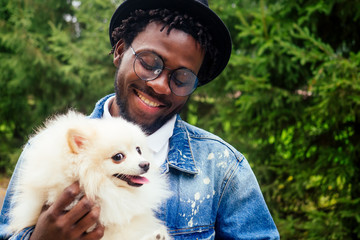 afro man hugging his fluffy spitz in park