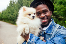Afro Man Hugging His Fluffy Spitz In Park
