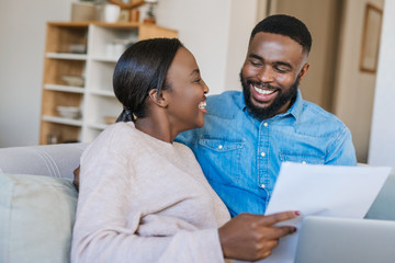 Wall Mural - Laughing African American couple doing online banking at home