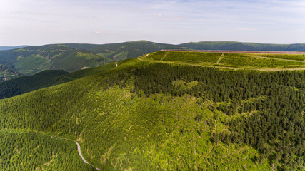 Wall Mural - Aerial view of the beautiful mountain landscape with mountain peaks covered with forest and a cloudy sky.