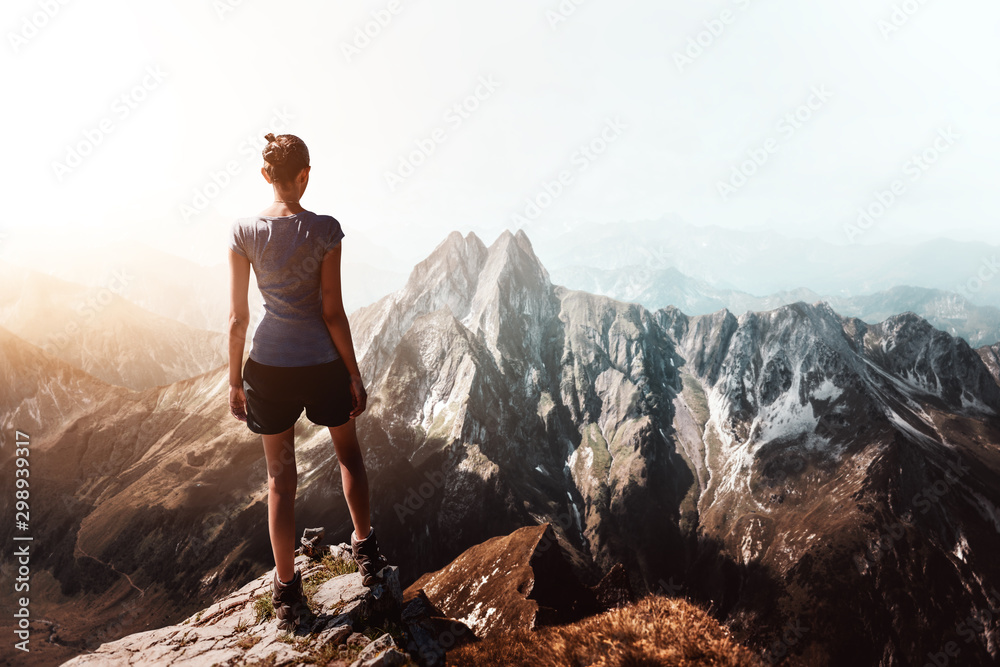 Hiker on peak with tall mountain in background - obrazy, fototapety, plakaty 
