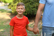 © New Africa - Little boy and his father holding hands outdoors. Family weekend
