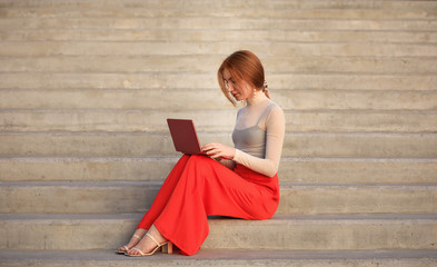 Poster - Beautiful young woman with laptop sitting on stairs outdoors