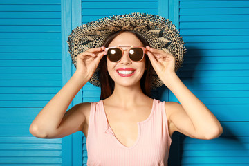 Beautiful woman wearing sunglasses and hat near blue wooden folding screen