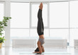 Young woman practicing supported headstand asana in yoga studio. Salamba Sirsasana pose