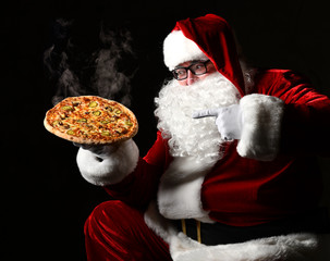 Wall Mural - Happy laughing Santa Claus hold big hot steaming original pizza offering pointing finger. New year and Merry Christmas fast food 