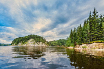 Wall Mural - orange dawn, sunset on the kama river in cloudy weather, rocky steep bank overgrown with forest.
