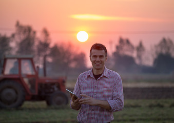 Canvas Print - Farmer with tablet in front of tractor