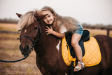 Adorable little girl riding a pony at summer
