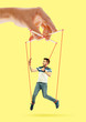 Man like a puppet in somebodies hands on yellow background. Concept of unfair manipulation, phycology of exploitation, mental technique, motivation. Puppets and their masters. Possessive relationship.