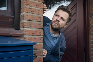 Handsome young man opening door looking on what his neighbor is doing.