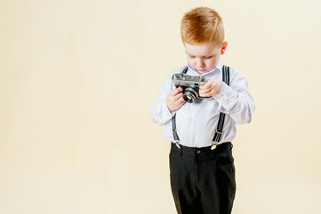 little red-haired boy with a retro camera in hands on an isolated light background