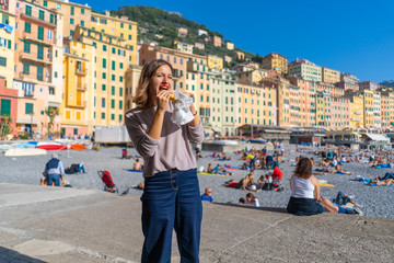 happy tourist having typical pizza focaccia di recco in the beach of Camoglia, Liguria, Italy. Food bloggers travelling around italy tasting traditional italian food