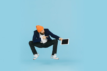 Wall Mural - Young caucasian businessman having fun dancing break dance on blue studio background. Management, flexible, freedom, professional occupation, alternative way of modern working. Loves his job