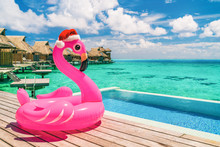 Christmas Beach Summer Vacation Flamingo Pool Float With Santa Hat Travel Background For Winter Holidays.