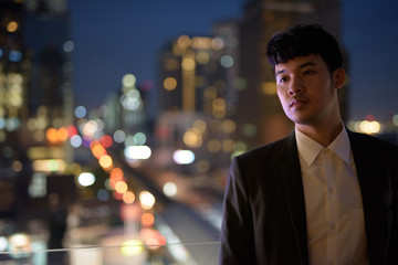 Wall Mural - Portrait of young Asian businessman against view of the city